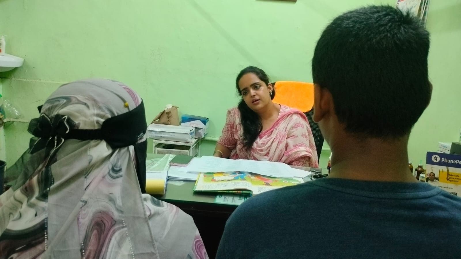 An IEC counsellor meeting a parent and adolescent at the OPD, both photographed from behind so neither is identifiable