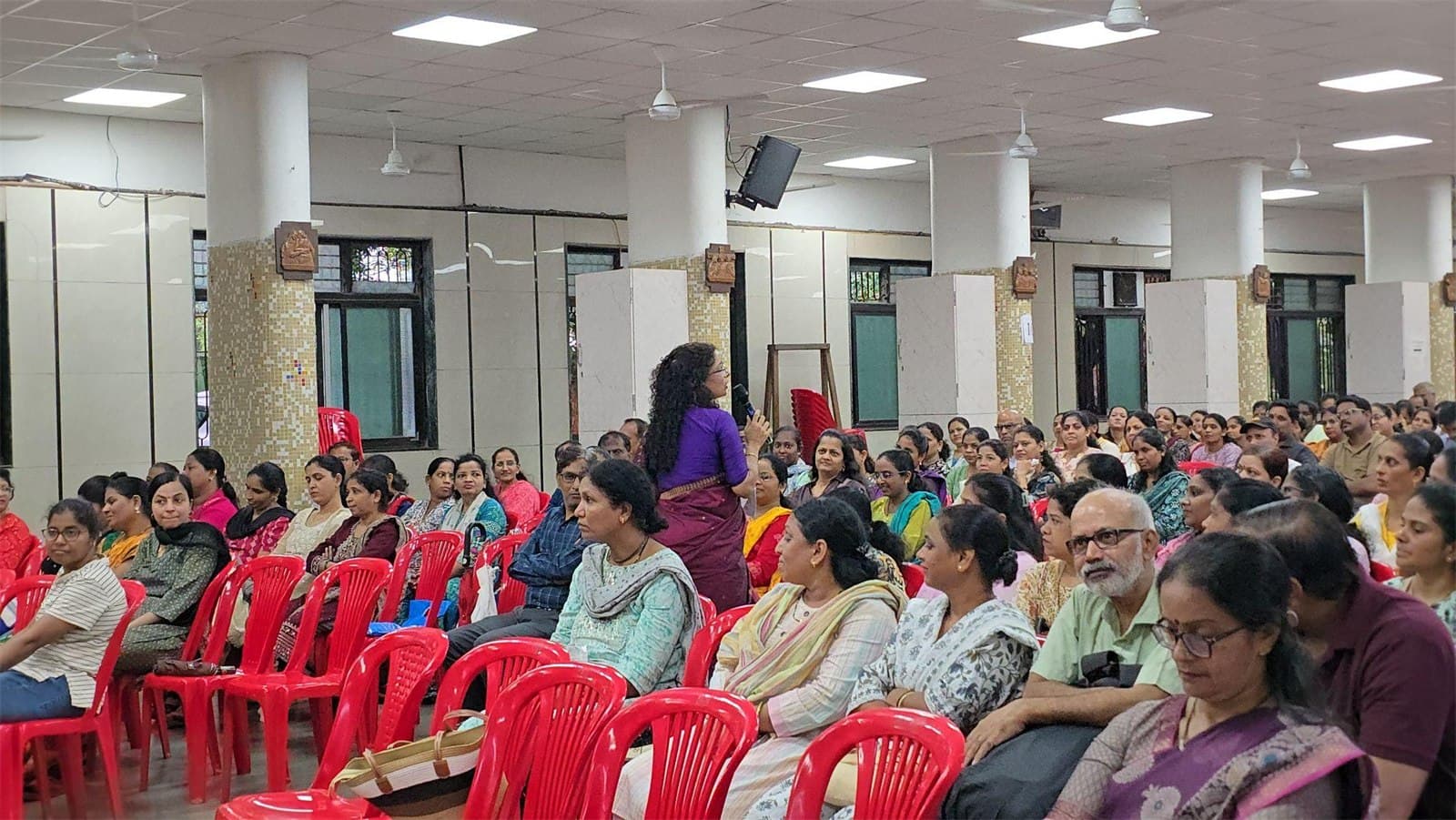A hall full of parents at an IEC session, with a facilitator taking questions